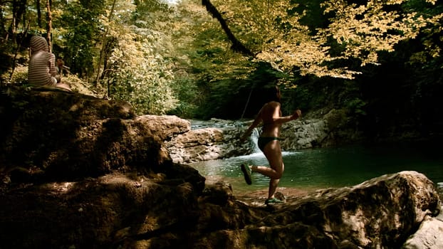 Beautiful tropical rain forest and a small lake. Creative. Woman in swimsuit walking near cold stream in the natural park at the spring or summer season