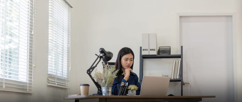 Asian businesswoman sitting at work with serious expression on her face at home.