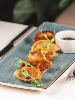Gyoza or Jiaozi Traditional Chinese and Japanese food. Row of fresh Jiaozi on plate in restaurant table interior. Taiwanese and Japanese Pan-fried gyoza dumpling jiaozi food in plate with soy sauce