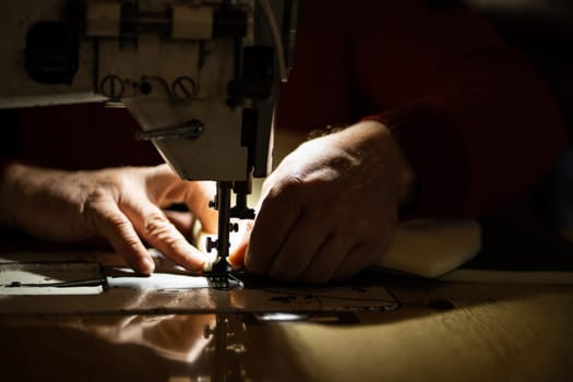 Sewing machine and men's hands of a tailor needle in focus