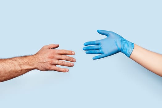 The men's hand and the woman's hand in the latex glove are drawn to each other. The photo symbolizes social distance and safety.