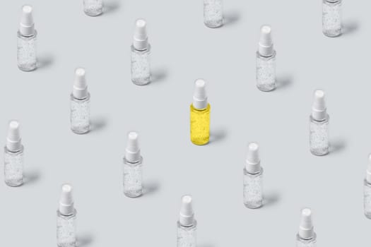 Pattern of bottles with gray and yellow filling on gray background. Advertising cosmetics in the trendy colors of the new year.