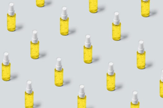 Pattern of bottles with yellow filling on gray background. Advertising cosmetics in the trendy colors of the new year.