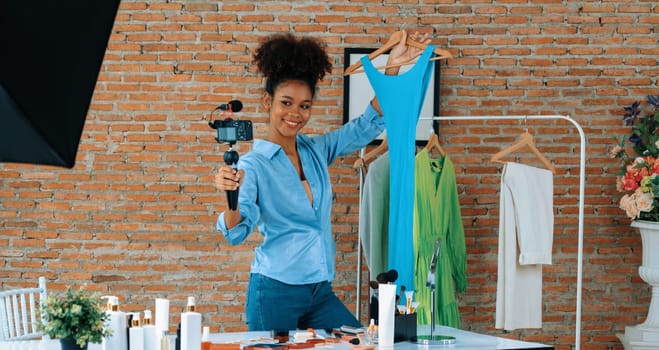 Woman influencer shoot live streaming vlog video review clothes crucial social media or blog. Happy young girl with apparel studio lighting for marketing recording session broadcasting online.