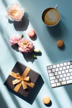 Freelancer holiday workplace. Blue table at the window with cappuccino, cakes, gift and flowers.