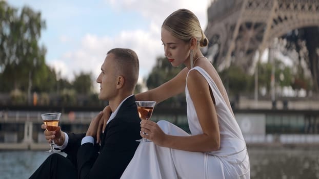 Elegant couple on date in Paris. Action. Beautiful elegant couple celebrate their anniversary on waterfront in Paris. Beautiful couple drinks wine on romantic date.