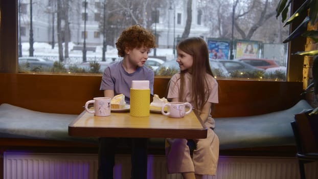 Girl and boy chat in cafe. Stock footage. Children communicate with each other in cafe. Two children they talk in cafe at lunch.