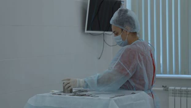 Preparation for the surgery. Action. Multiple surgery tools on the table in operating room, scrub nurse in rubber gloves