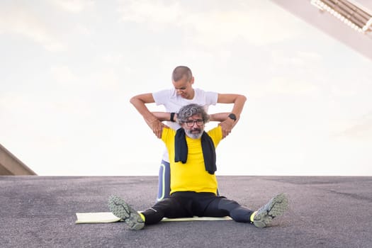senior sports man stretching arms with help of his personal trainer during workout, concept of active and healthy lifestyle in middle age, copy space for text