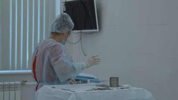 Preparation for the surgery. Action. Multiple surgery tools on the table in operating room, scrub nurse in rubber gloves