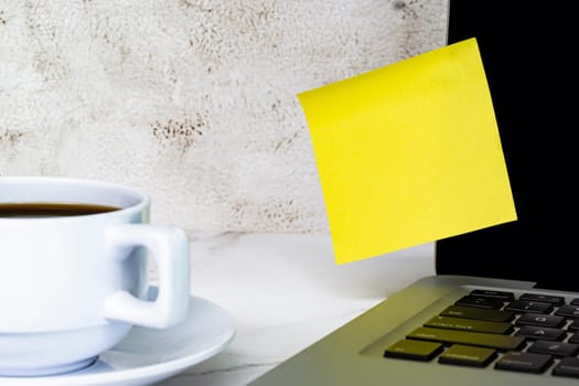Yellow sticky note on a notebook with coffee. Copy space.