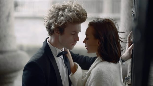 Young bride and groom posing in a city on a windy day. Action. Young woman in white dress and a man in suit in the city outdoors