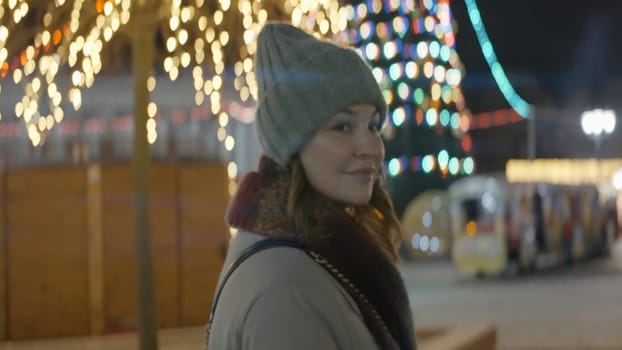 Beautiful woman goes to Christmas tree at night. Action. Night walk through decorated Christmas city. Woman walks around New Year's city at night in winter.