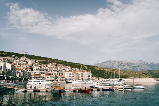 Motor and sailing yachts are moored off the coast of Lustica Bay against the backdrop of colorful villas. Montenegro. High quality photo