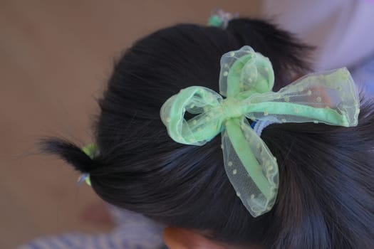 Beautiful ribbon is tied on a child hair .