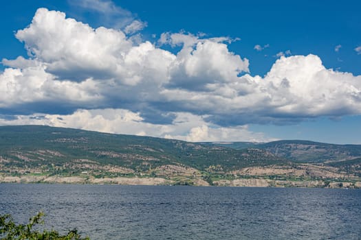 Overview of Okanagan lake with mountains and clouds on blue sky background
