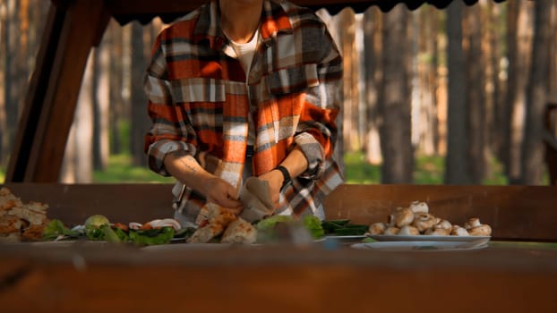 Woman serving table at outdoors picnic. Stock footage. Summer forest and bbq