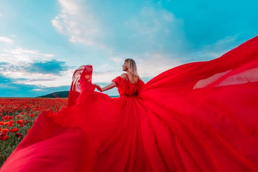 Woman poppy field red dress. Happy woman in a long red dress in a beautiful large poppy field. Blond stands with her back posing on a large field of red poppie