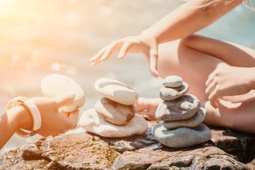 Balanced Pebbles Pyramid on the Beach on Sunny Day and Clear Sky at Sunset. Blue Sea on Background Selective focus, zen stones on sea beach, meditation, spa, harmony, calm, balance concept.