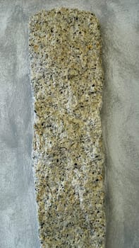 A granite pillar protrudes from a reinforced concrete wall of a building.