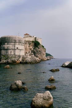 Large boulders peek out of the sea near Bokar Fortress. Dubrovnik, Croatia. High quality photo