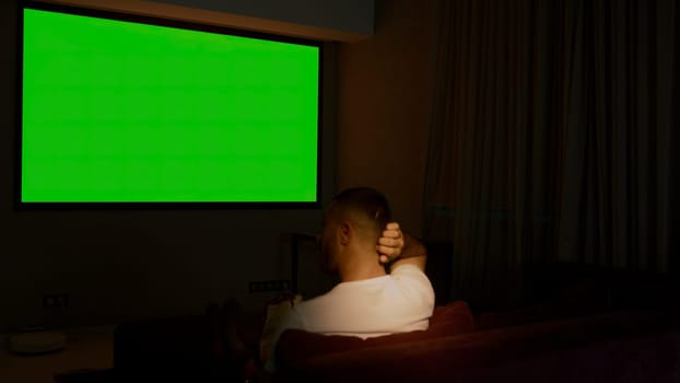 Viewing on a projector in a closed room. Media. A man looking into a green screen that is shown on a large screen. High quality 4k footage