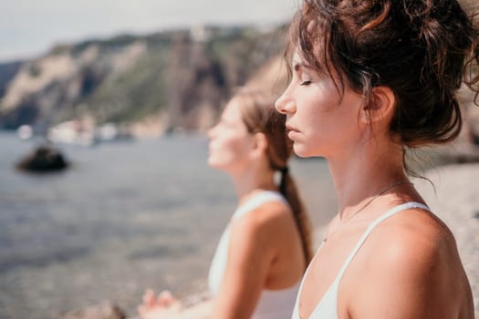 Woman sea yoga. Back view of free calm happy satisfied woman with long hair standing on top rock with yoga position against of sky by the sea. Healthy lifestyle outdoors in nature, fitness concept.