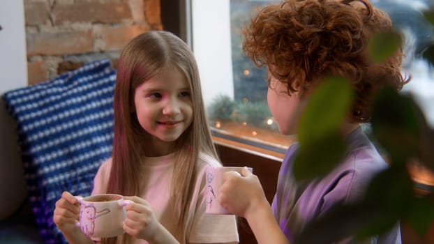 Boy and girl children eating cakes and drinking milk at the restaurant. Stock footage. Kids communicating and heaving desserts