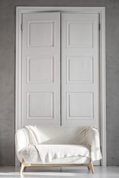 A beautiful room with tall white wooden doors and a white sofa against the background of the doors. Studio for photography in vintage style.