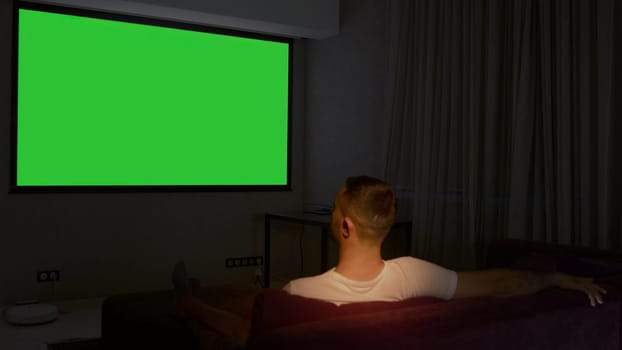 Viewing on a projector in a closed room. Media. A man looking into a green screen that is shown on a large screen. High quality 4k footage