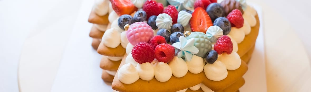 Homemade naked layered vanilla cake with whipped cream and fresh berries on top on a gray concrete background. Summer cake. Copy space