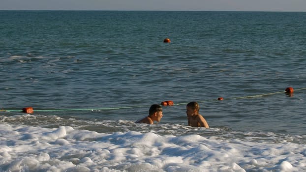 Slow motion of boys bathing in the sea and catching waves. Creative. Children playing in the sea with strong waves
