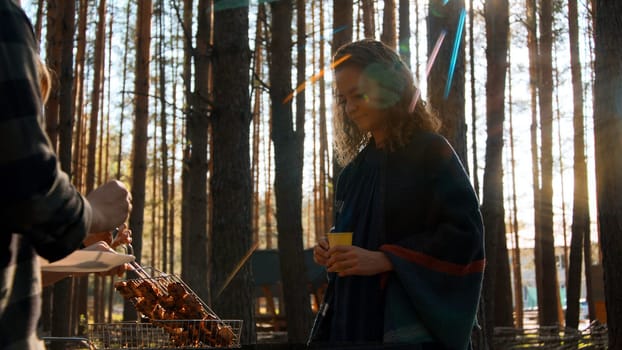 Woman with pine trees and shining sun on the background. Stock footage. Outdoors picnic with friends on an autumn day
