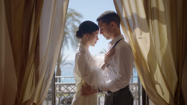 Cute couple posing against the background of windows in the apartment. Action. A young man with his girlfriend on a date at home with the bright light of the sun from the window. High quality 4k footage