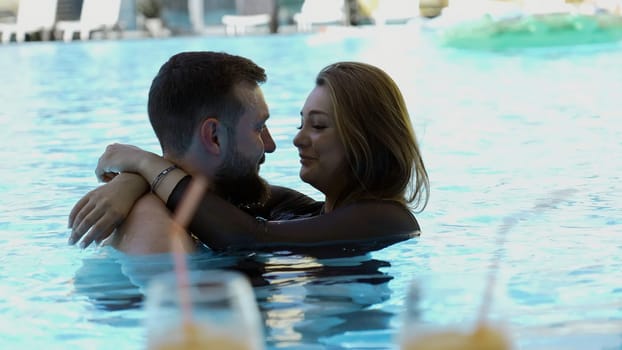 Happy couple embracing in outdoors swimming pool. Clip. Man and woman on a vacation
