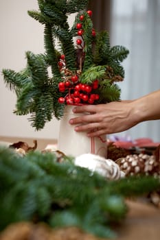 Woman making Christmas arrangement with fir branches. craft handmade decor.