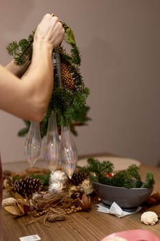Woman making Christmas arrangement with fir branches. craft handmade decor.