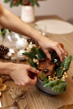 Woman making Christmas arrangement with fir branches. craft handmade decor.