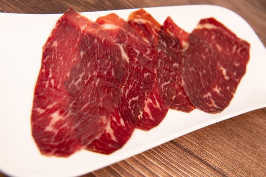 Dry-cured Spanish ham, Serrano ham, Bellota ham, Italian prosciutto crudo or Parma ham, wagyu slice. High quality photo