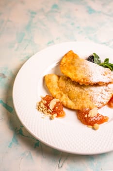 top view of sweet pasties with sugar sprinkles on a white plate.