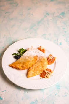 sweet pasties with sugar sprinkles on a white plate.