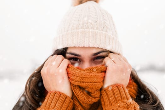 Color of the year 2024: Peach Fuzz. Winter season. Portrait of a beautiful smiling woman in sweater and hat in snowy park