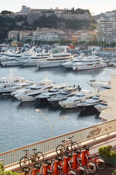 Monaco, Monte Carlo, 18 October 2022: Sunset panorama of port Hercule, moored mega yacht, sun reflection. High quality photo