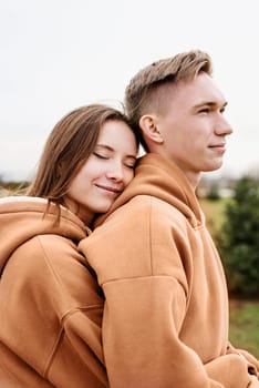 Color of the year 2024: Peach Fuzz. Valentines Day. young loving couple wearing trendy colored peach fuzz sweatshirts hugging outdoors