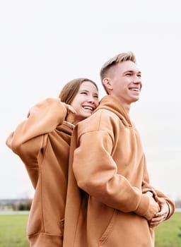 Color of the year 2024: Peach Fuzz. Valentines Day. young loving couple wearing trendy colored peach fuzz sweatshirts hugging outdoors