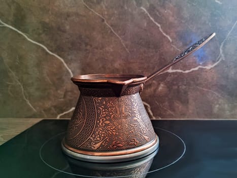 cezve on a glass-ceramic stove on a brown background close-up