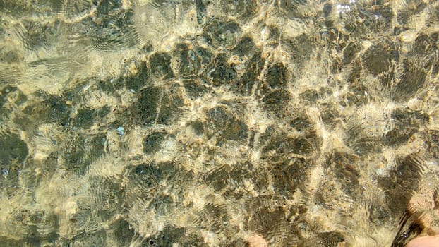 clean transparent sea water in shallow water in which sunlight is reflected.