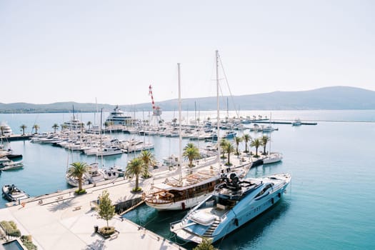 Sailboat is moored to the corner pier next to a motor yacht. High quality photo