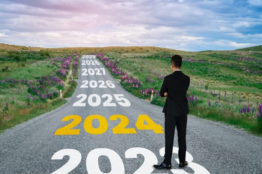 2024 New Year journey and future vision concept . Businessman traveling on highway road leading forward to happy new year celebration in beginning of 2024 for bliss and successful start .