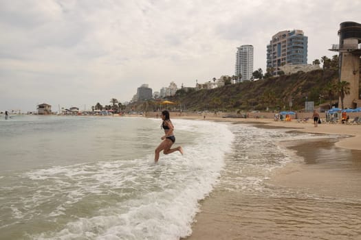 20 June 2023 Netanya Israel, beach sand and sea water, women go,summer . High quality photo